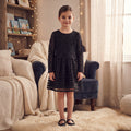 Robe fille noire portée, haut en dentelle fleurie à manches longues et jupe évasée à bandes transparentes