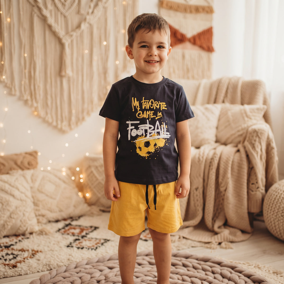 Ensemble garçon football porté, t-shirt bleu marine à ballon jaune et short jaune à cordon noir