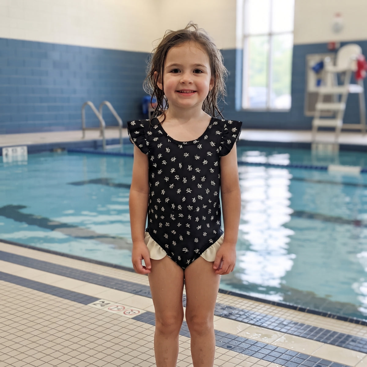 Maillot de bain fille une pièce porté, noir à petits motifs blancs avec volants aux épaules et aux hanches