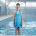Maillot de bain turquoise fille porté, col en V, liens noués au cou et jupette à pointes